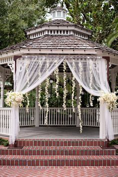 a gazebo decorated with white flowers and greenery