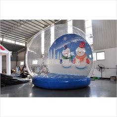 an inflatable snow globe with two snowmen on it, inside a warehouse