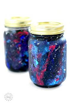 two jars filled with blue, red and purple liquid sitting on top of a white surface