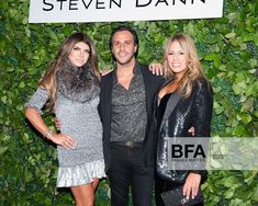 two women and a man standing next to each other in front of a green wall