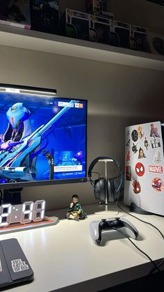 a computer monitor sitting on top of a desk next to a game controller and headphones