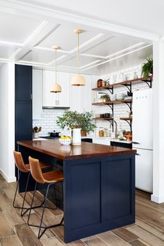 a kitchen with white cabinets and blue island in the center, surrounded by wooden flooring