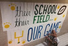 a man kneeling down next to a sign that says their school is field our game