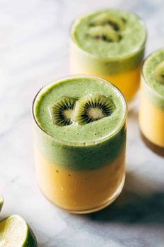 two glasses filled with green smoothie and kiwi slices