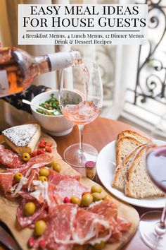 a person pouring wine into a glass on top of a table filled with meat and cheeses