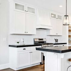 a large kitchen with white cabinets and black counter tops, along with an island in the middle