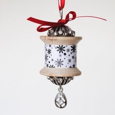 an ornament hanging from a wooden pole with red ribbon and bells on it