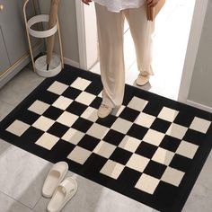 a black and white checkerboard rug on the floor next to a pair of slippers