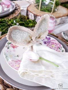 a table set for easter with bunny ears on top of the plates and napkins