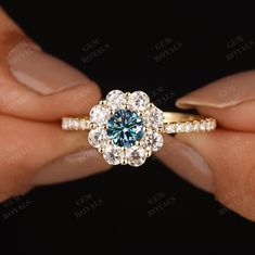 a woman's hand holding an engagement ring with blue and white diamonds on it