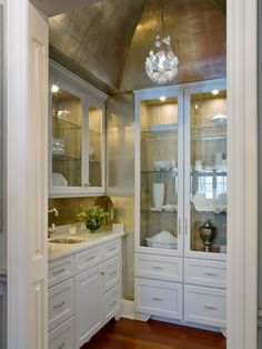 a kitchen with white cabinets and marble counter tops, along with glass doors that lead into the pantry