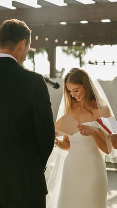 a bride and groom reading vows at their wedding ceremony