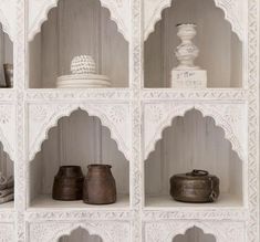 several shelves with vases and other decorative objects on top of each shelf, all in white