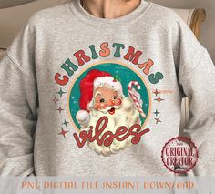 a woman wearing a christmas sweatshirt with santa clause on it's chest and holding a candy cane