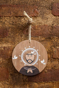 a wooden plaque with a man's face and birds on it hanging from a rope