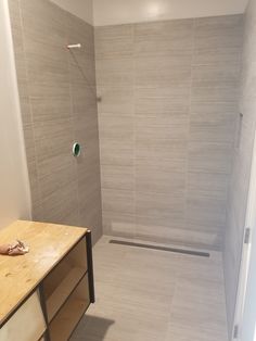 a walk in shower sitting next to a wooden table