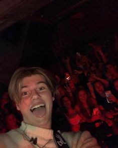 a young man with his mouth open in front of a large group of people at a concert