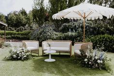 an outdoor seating area with umbrellas and flowers on the grass in front of it