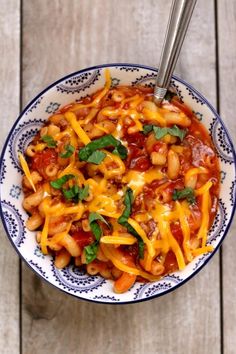 a bowl filled with pasta and cheese on top of a wooden table