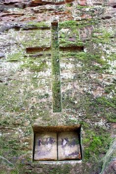 an old stone wall with moss growing on it and a small window in the middle