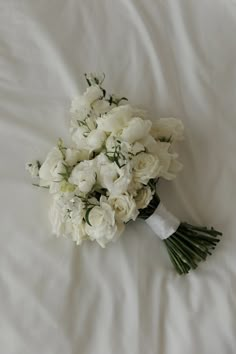 a bouquet of white flowers laying on top of a bed