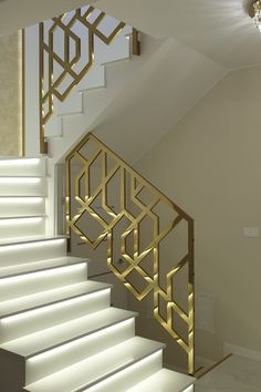 a white staircase with gold railing and chandelier