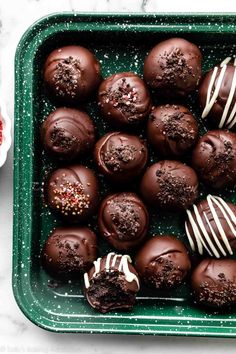 chocolate truffles in a green tray with white frosting and sprinkles