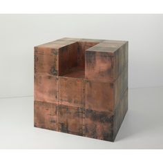 a brown cube shaped object sitting on top of a white floor next to a wall