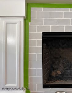 a fire place in the corner of a room with green painted walls and white cabinets