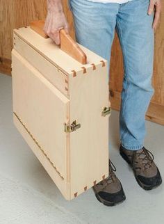 a man is holding a wooden box in his hands while standing on the floor next to it