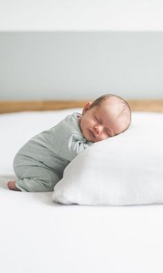 a baby sleeping on top of a white pillow