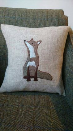 a pillow with a fox on it sitting on top of a green couch next to a wall