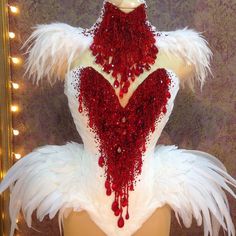 a mannequin with red beads and white feathers on it's back, in front of a mirror