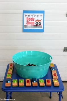 a blue table topped with a green bowl filled with blocks next to a sign that says body shop