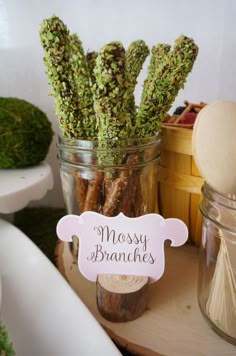 there is a jar full of mossy branches on top of a table next to other items