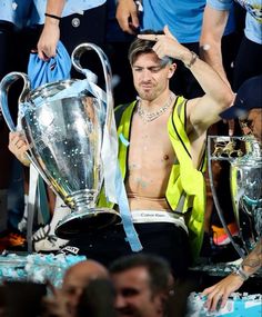 a shirtless soccer player holding the trophy