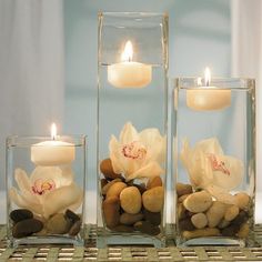 three glass vases filled with rocks and candles