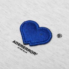 a blue heart patch on the back of a white t - shirt that says ader error