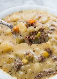 a spoon full of soup with meat and vegetables on it, in a white bowl