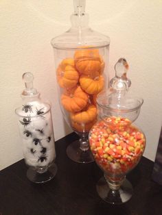 three glass containers filled with candy sitting on top of a table next to each other