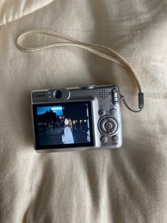 a camera is laying on a bed with a strap around it's neck and the screen has an image of a bride