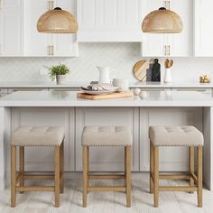 a kitchen island with two stools in front of it and some lights above it