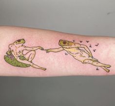 a person with a tattoo on their arm holding onto a frog that is floating in the air