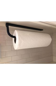 a roll of toilet paper is hanging from a black pipe on the wall next to a white brick wall