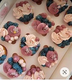 a box filled with lots of cupcakes covered in pink and blue frosting