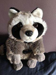 a stuffed raccoon sitting on top of a bed