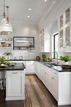 a large kitchen with white cabinets and black counter tops, along with wooden flooring