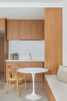 a kitchen with wooden cabinets and white counter tops next to a dining room table in front of a sink