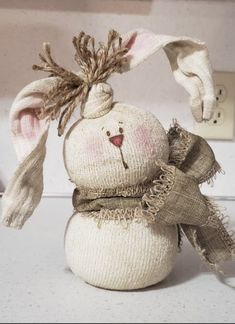 a white stuffed animal with a scarf around it's head and ears, sitting on top of a counter