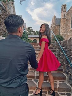 a man standing next to a woman in a red dress on top of some steps